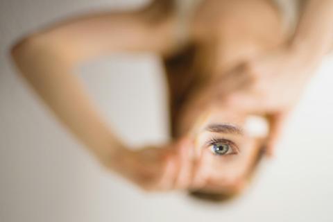 A distorted, inverted image of a woman looking through a magnifying glass.