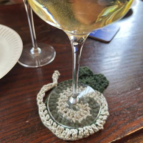 A cocktail glass atop a croched cat coaster