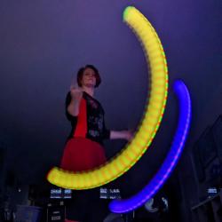 Emma spins brightly coloured LED Poi in a dark room.