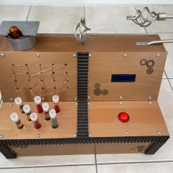 A wooden box with test tubes, screen, lights, and a big red button