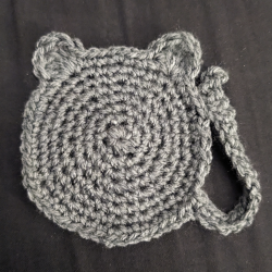 A crocheted coaster in with ears and a tail.